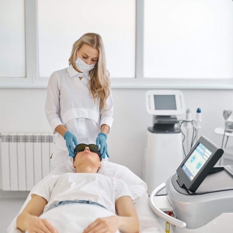 Cosmetician putting protective goggles on female client. Cosmetologist preparing client for facial laser carbon peeling procedure. Cosmetology and beauty concept